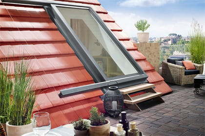 Ein Dach mit einem großen Dachfenster-Element was als Tür mit einer Treppe genutzt wird.
